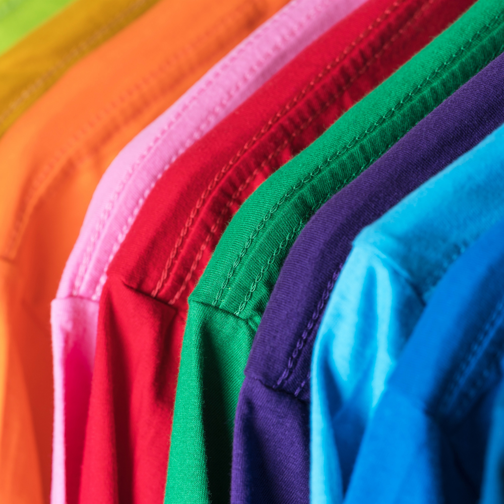 Stack of colorful folded shirts in various hues.